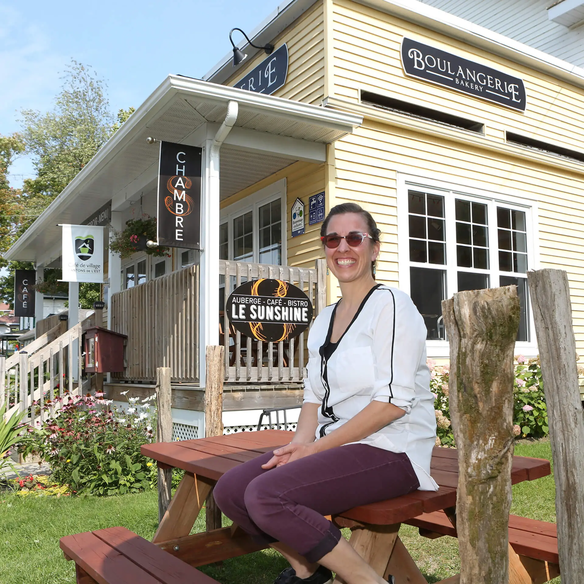 Femme souriante devant une boulangerie café de village