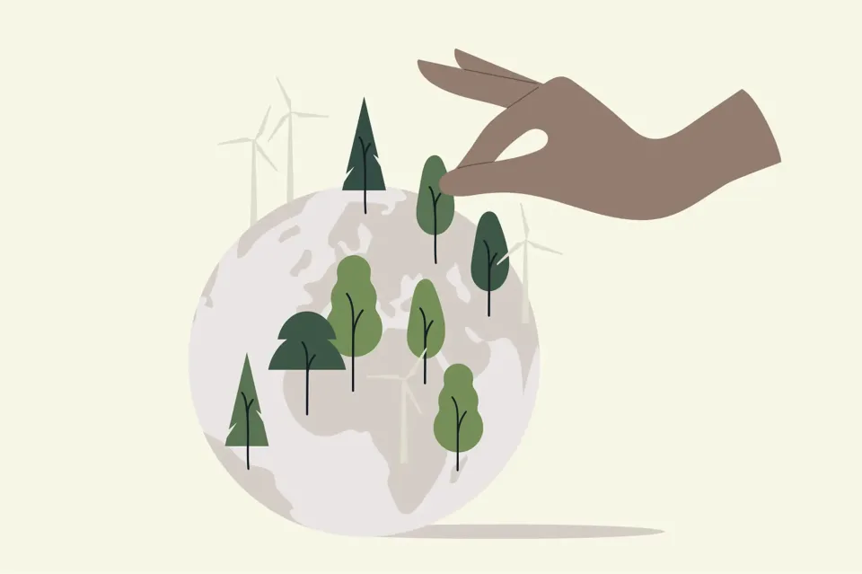 Hand placing trees on globe with wind turbines