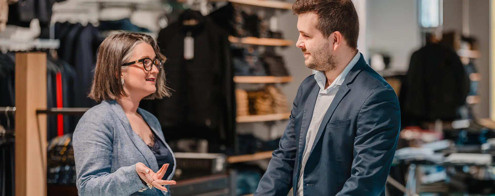 Two people discussing in clothing store showroom