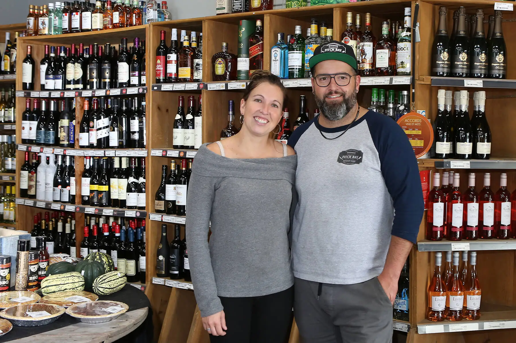 Couple souriant devant étagères de vins