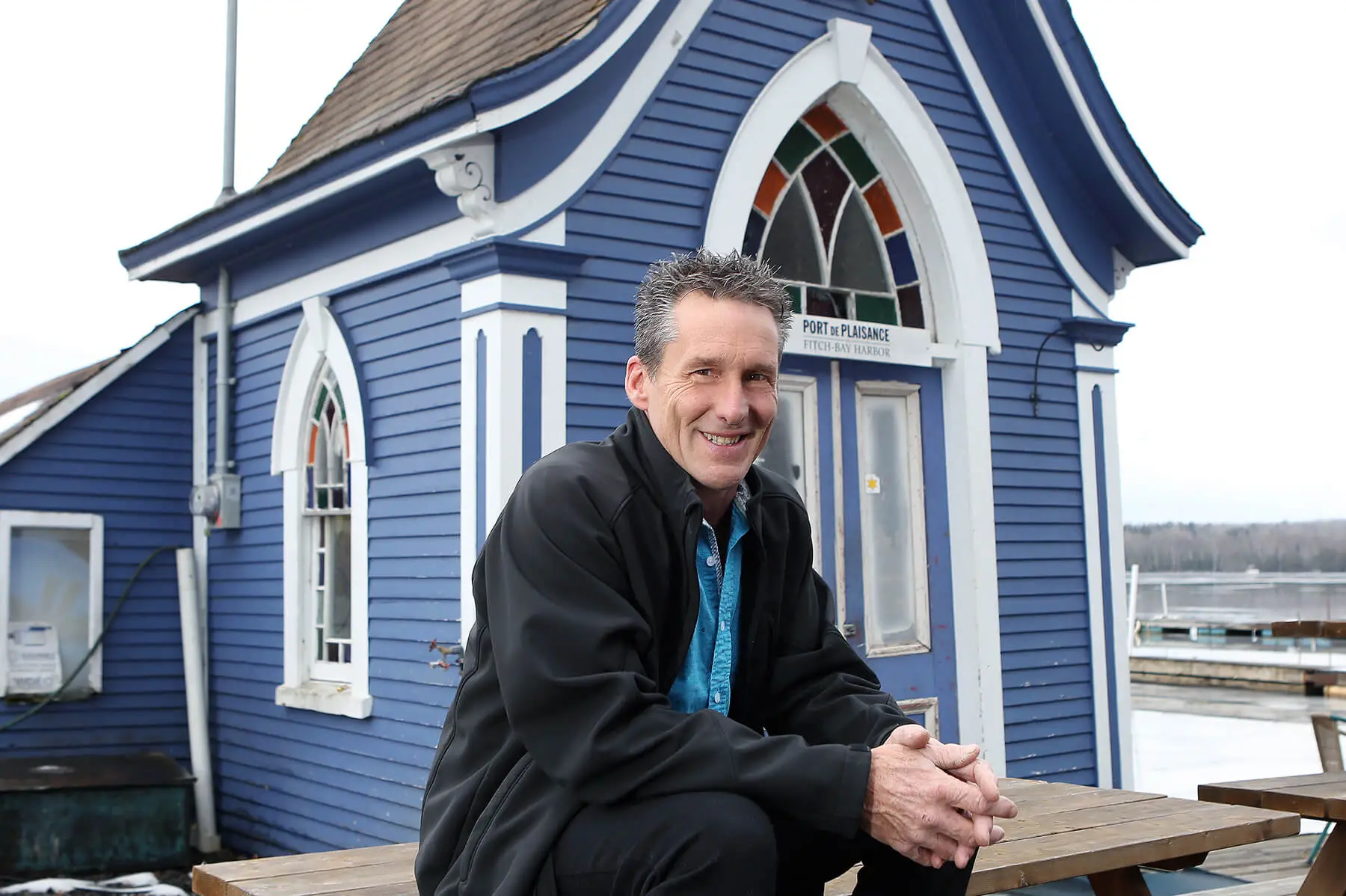 Homme souriant devant bâtiment bleu