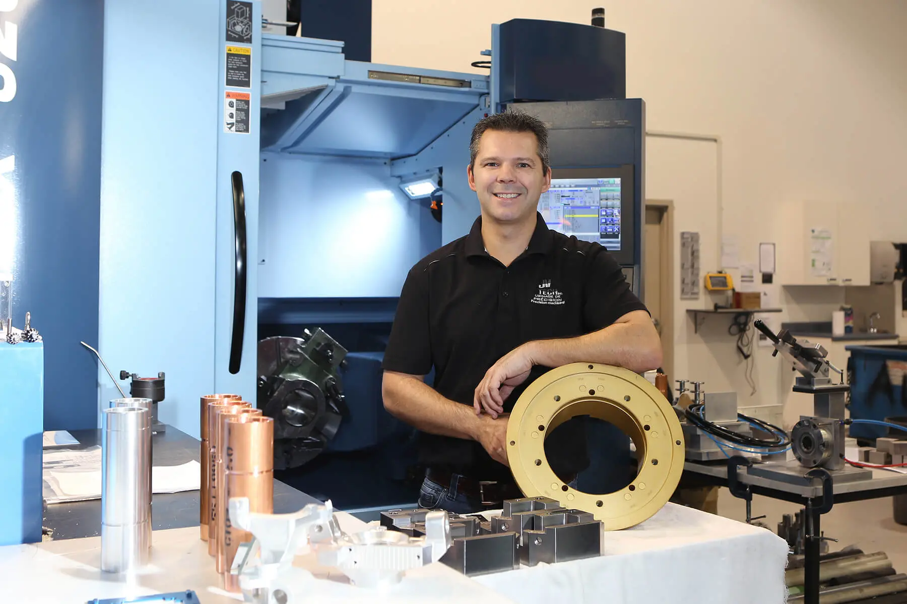 Engineer standing by CNC machine with metal parts