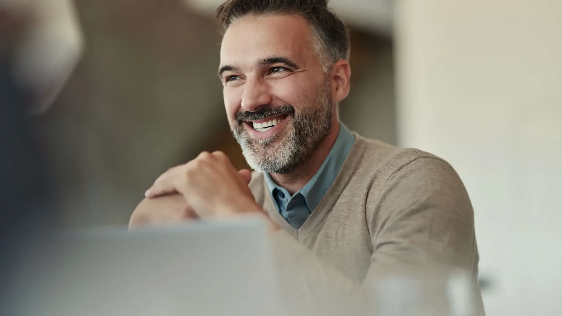Homme barbu souriant assis en intérieur