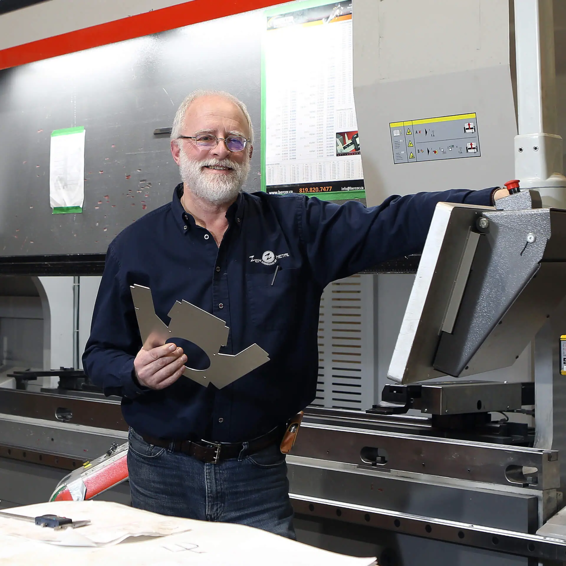 Technicien souriant tenant pièce métallique en atelier industriel