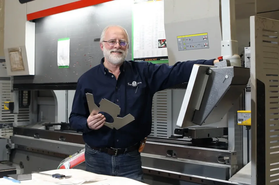 Technicien tenant pièce métallique dans atelier industriel