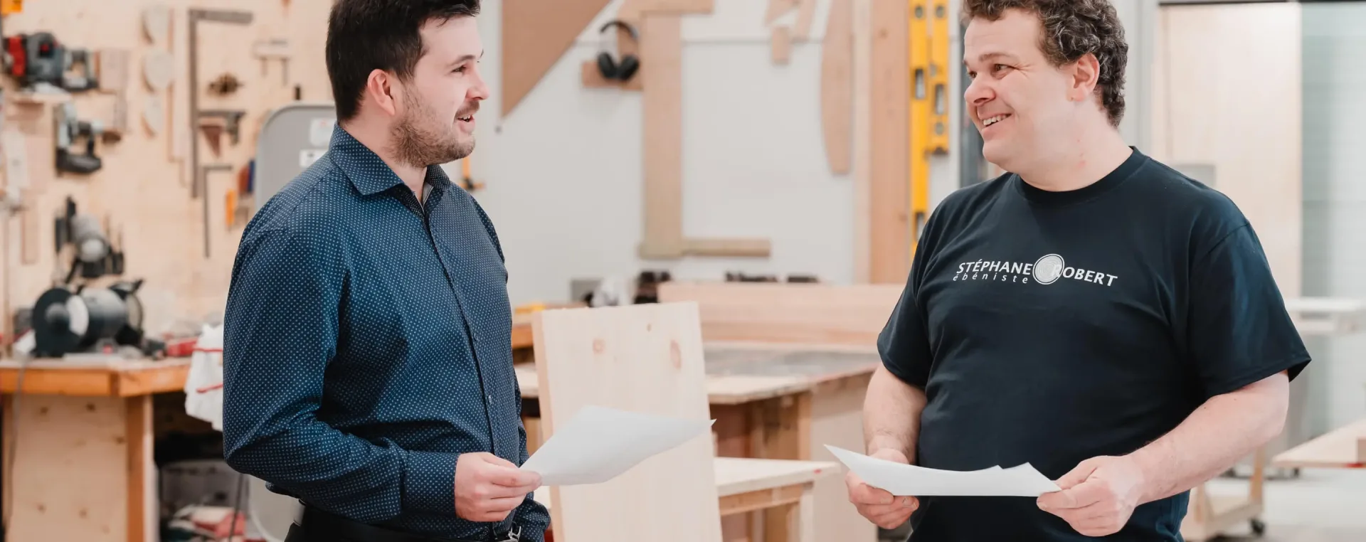 Two men discussing plans in woodworking workshop