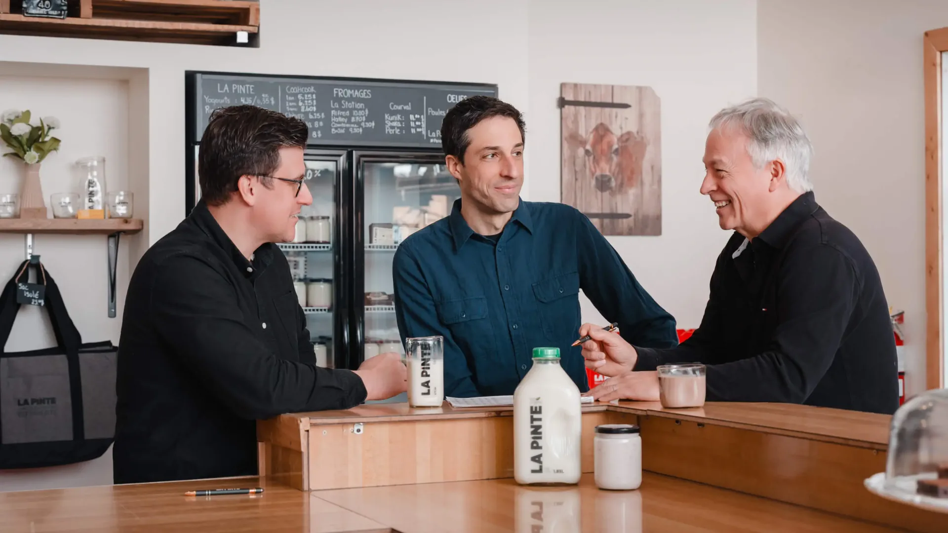 Three men chatting at dairy shop counter