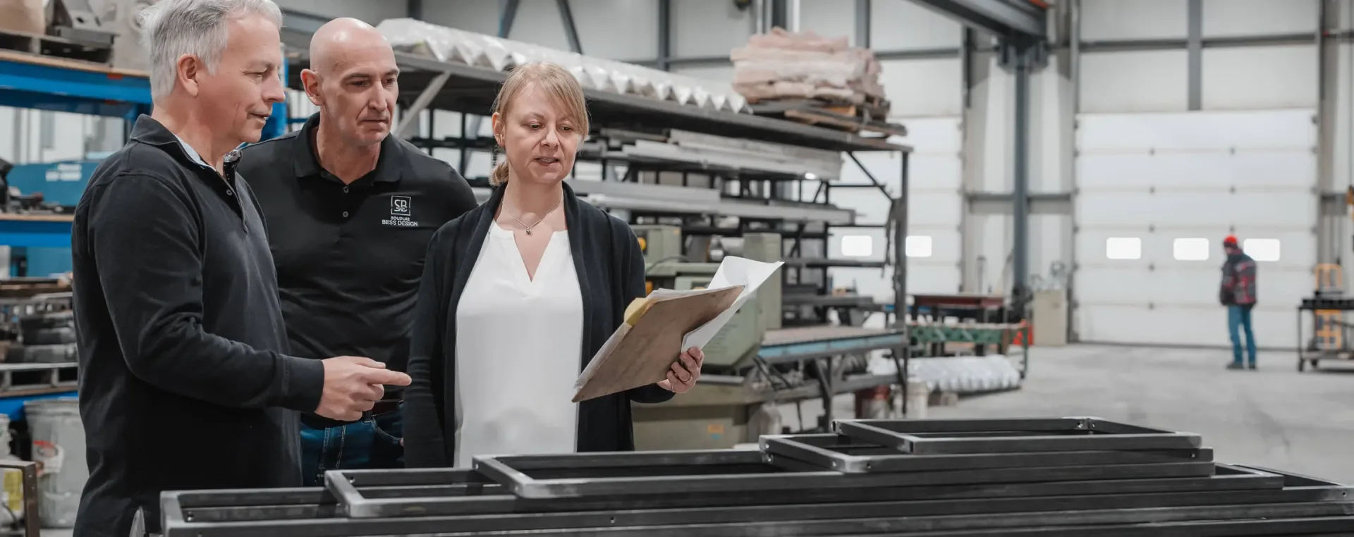 Trois professionnels examinent plans dans atelier industriel