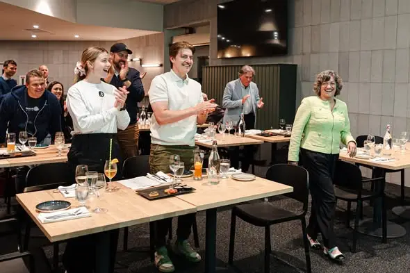 hommes et femmes heureux debout autour de tables en bois